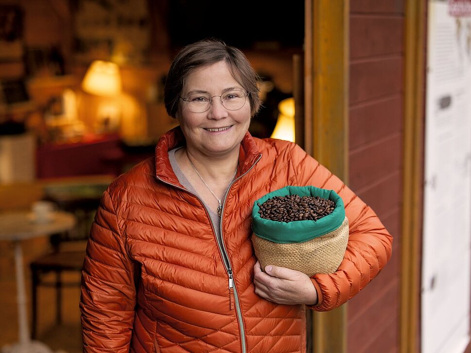 Frau hält ein Eimer mit Kaffeebohnen