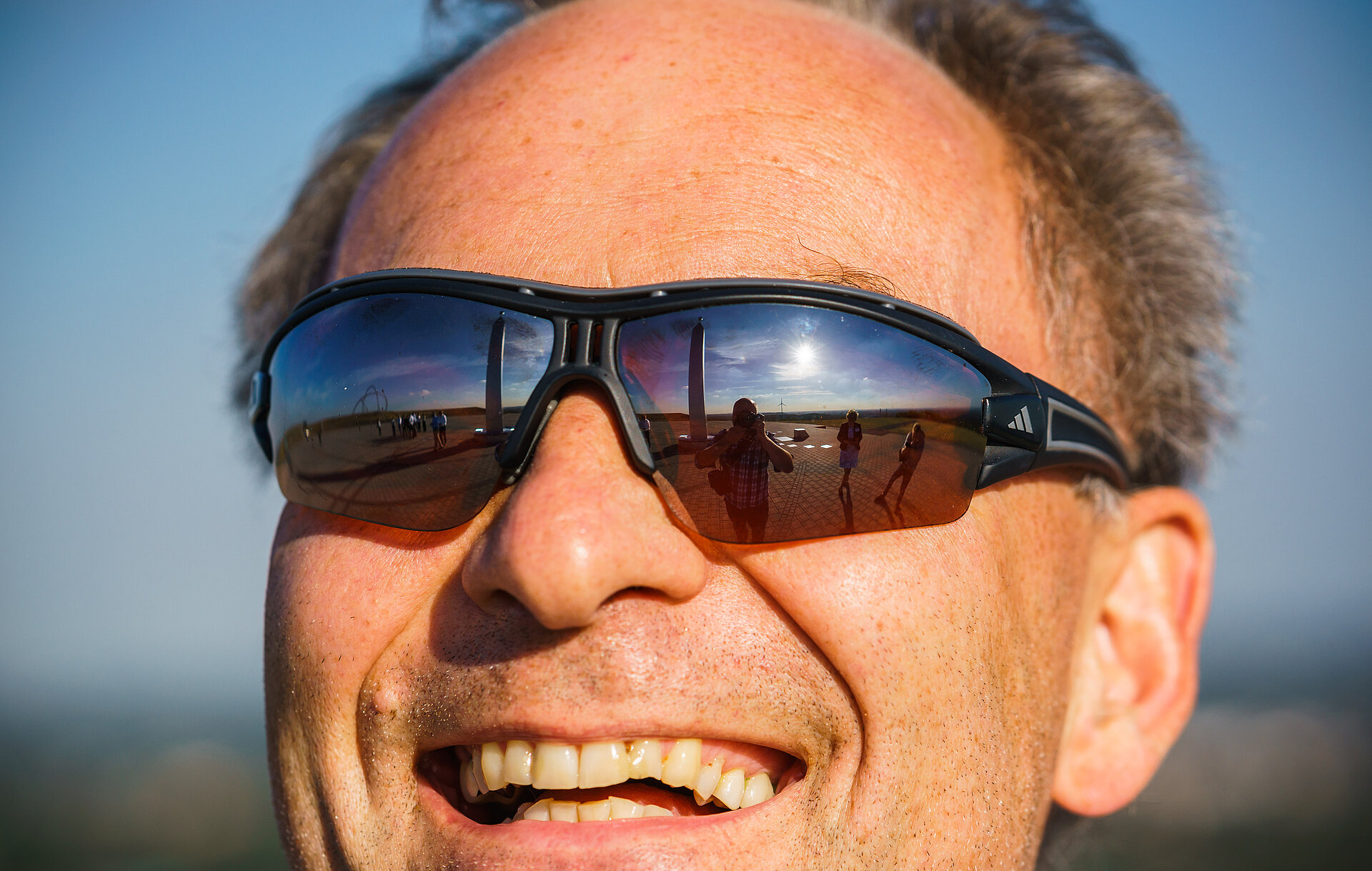 Das Bild zeigt einen lächelnden Herrn mit Sonnenbrille im Portrait.