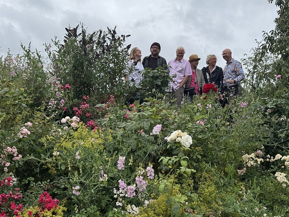 6 Personen stehen hinter Rosen