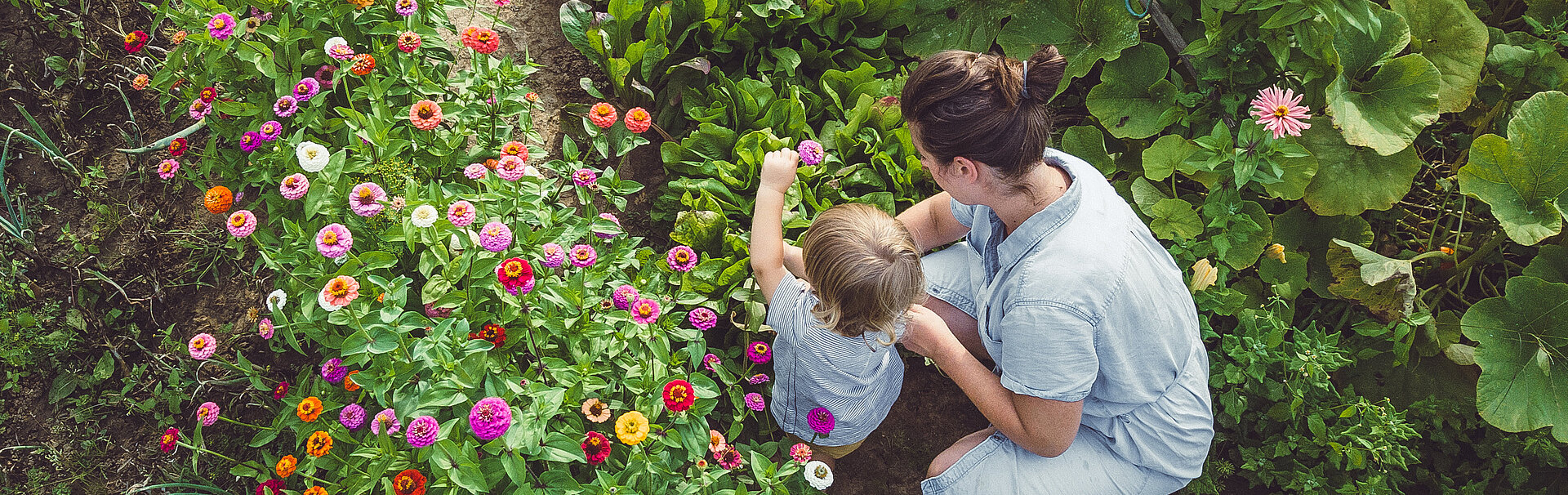 Frau mit Sohn an einem Blumenbeet