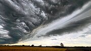Extremwetterereignisse in NRW Das Bild zeigt eine von links nach rechts ziehende Gewitterwolke über einer offenen Landschaft