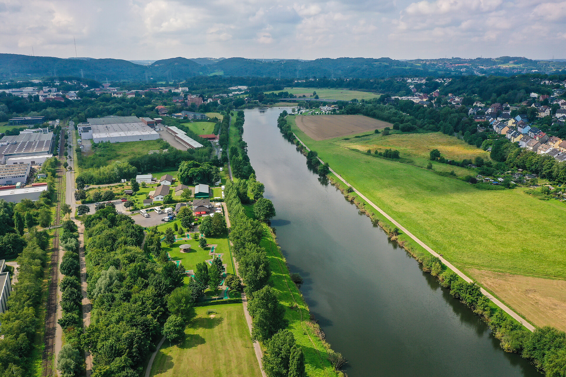 Vogelperspektive auf die Ruhr und einen seitlichen Weg. Drum herum Felder und Wohnhäuser