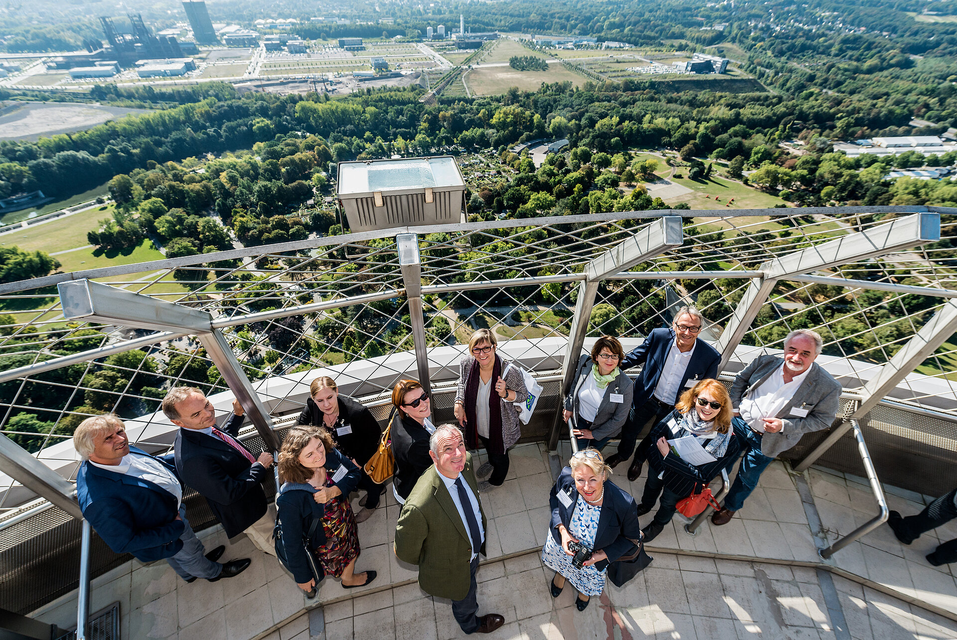 Das Bild zeigt eine Gruppe Menschen, die auf dem Florianturm stehend nach oben in die Kamera blicken.
