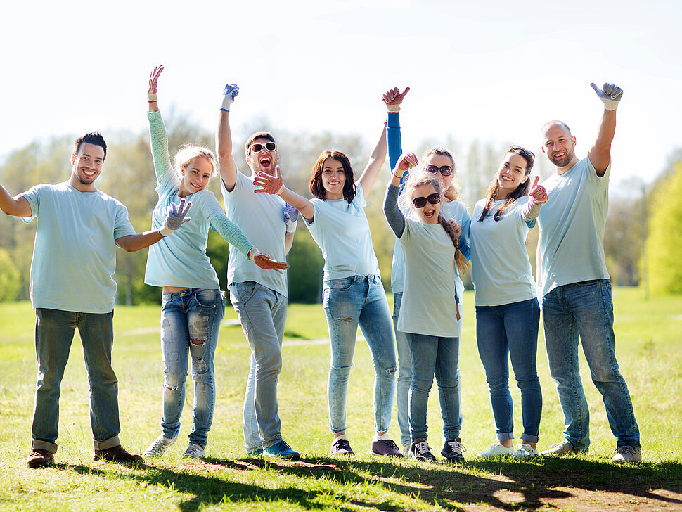 Eine Gruppe von jungen Menschen stehen im Park und strecken den Daumen hoch