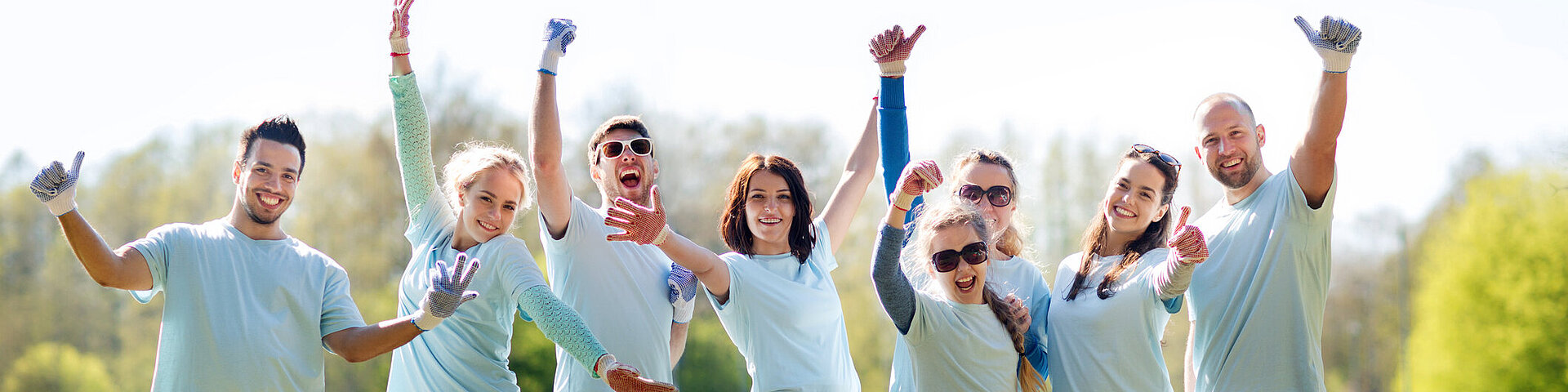 Eine Gruppe von jungen Menschen stehen im Park und strecken den Daumen hoch