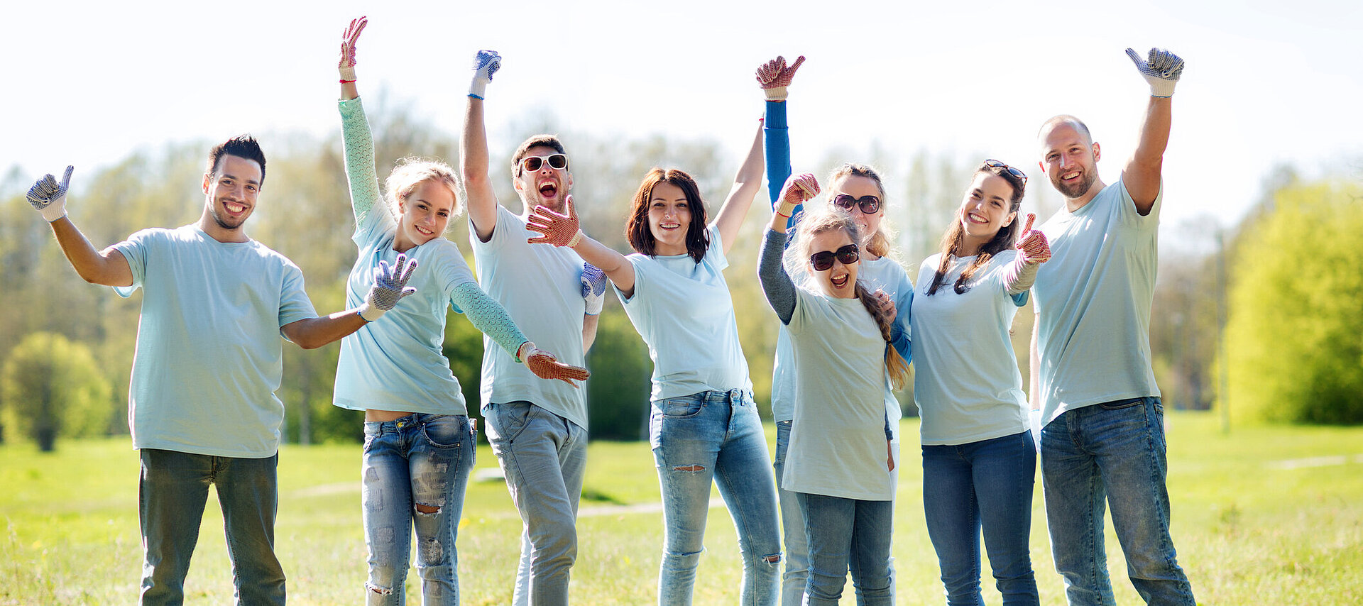 Eine Gruppe von jungen Menschen stehen im Park und strecken den Daumen hoch
