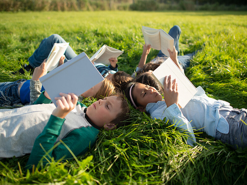 Youth Reading Together in the Grass Outside stock photo