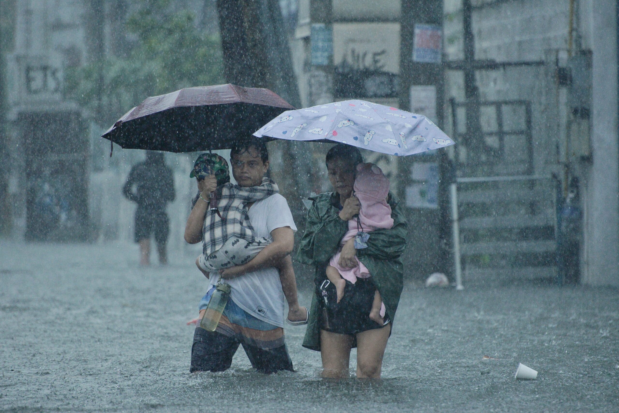 Geflutete Straßen in Quezon City, Philippines Zu sehen ist eine Familie mit zwei Kindern, die ihr Zuhause aus Sicherheitsgründen verließ, als der Taifun Carina am 24. Juli 2024 massive Überschwemmungen verursachte.
