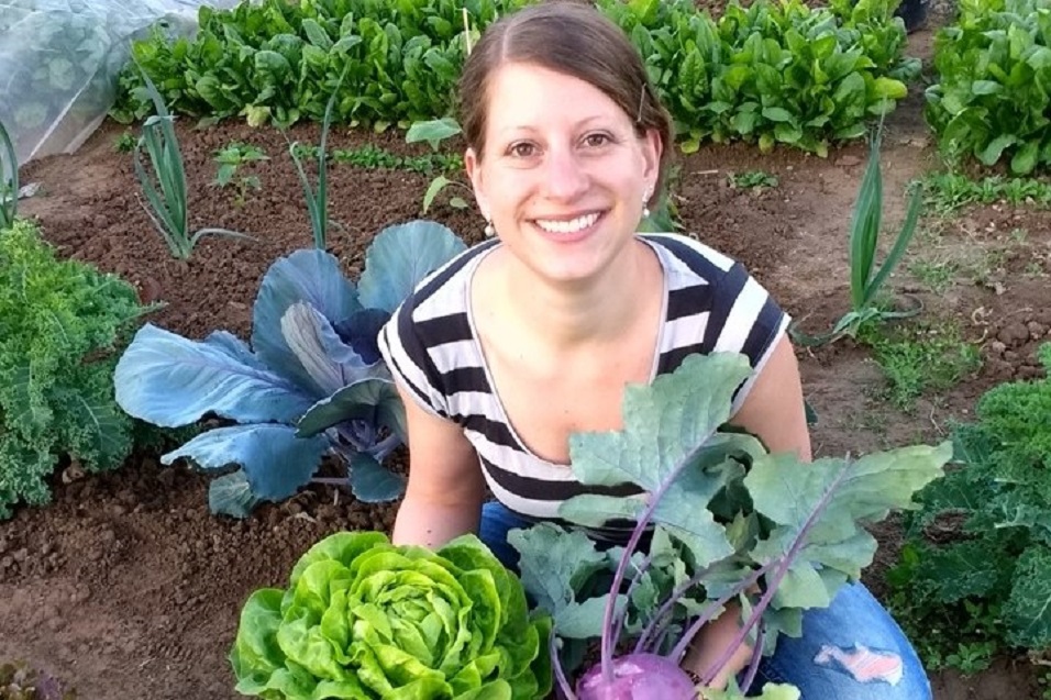 Mietgarten Düsseldorf Eine Gärtnerin, die geernteten Salat und Kohlrabi präsentiert