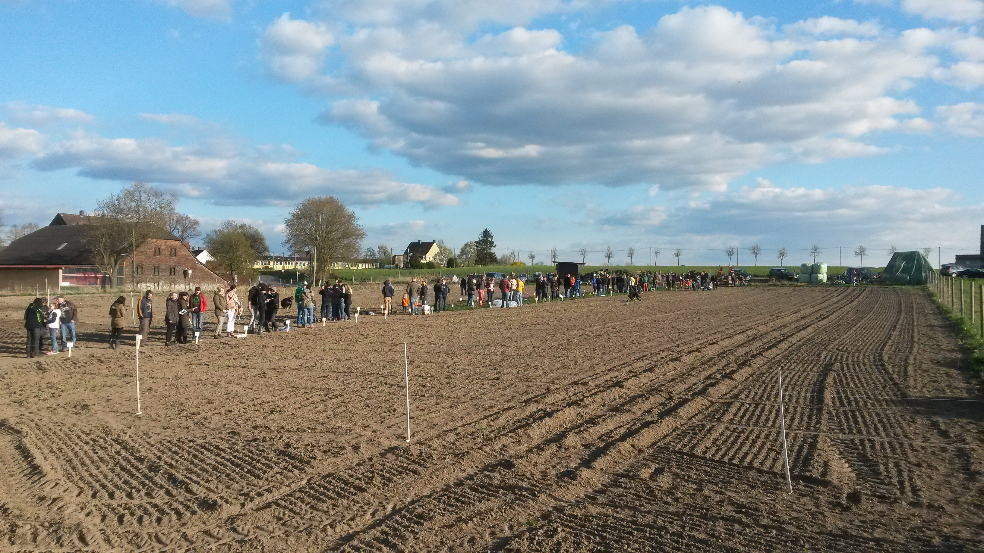Mietgarten Dortmund ein frisch eingesätes Feld und Menschen, die ihre Gartenparzellen in Empfang nehmen