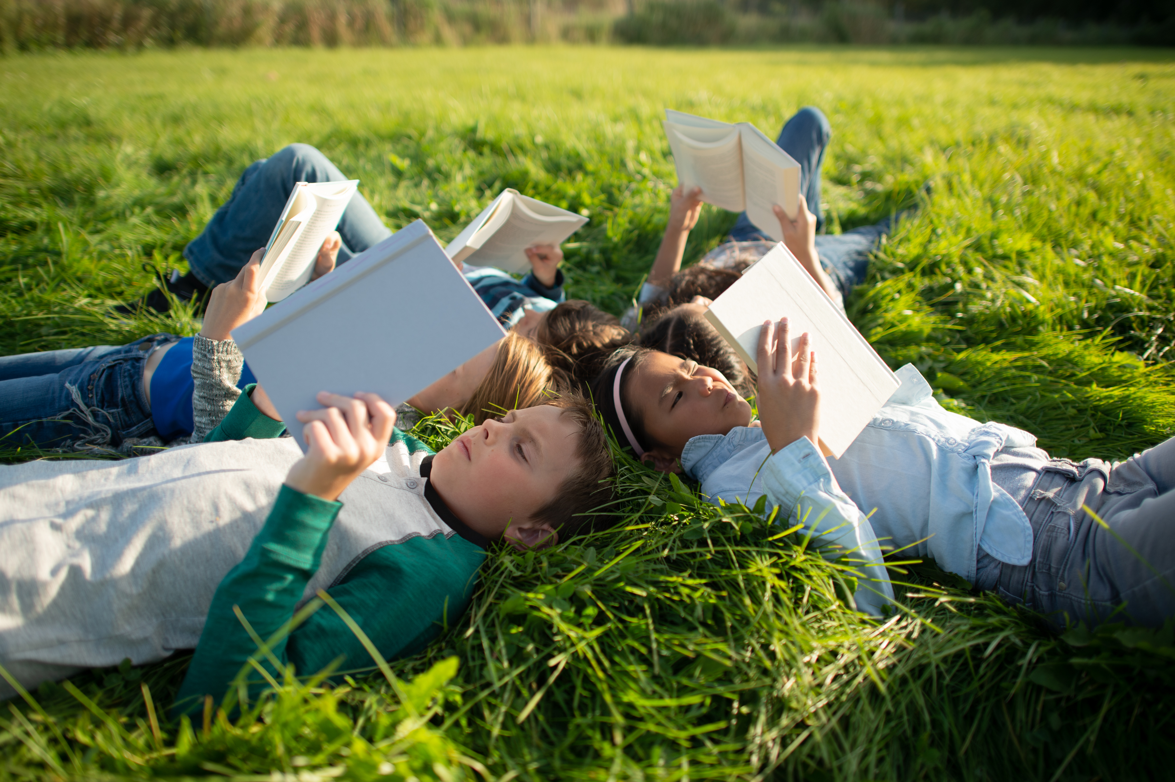 Youth Reading Together in the Grass Outside stock photo