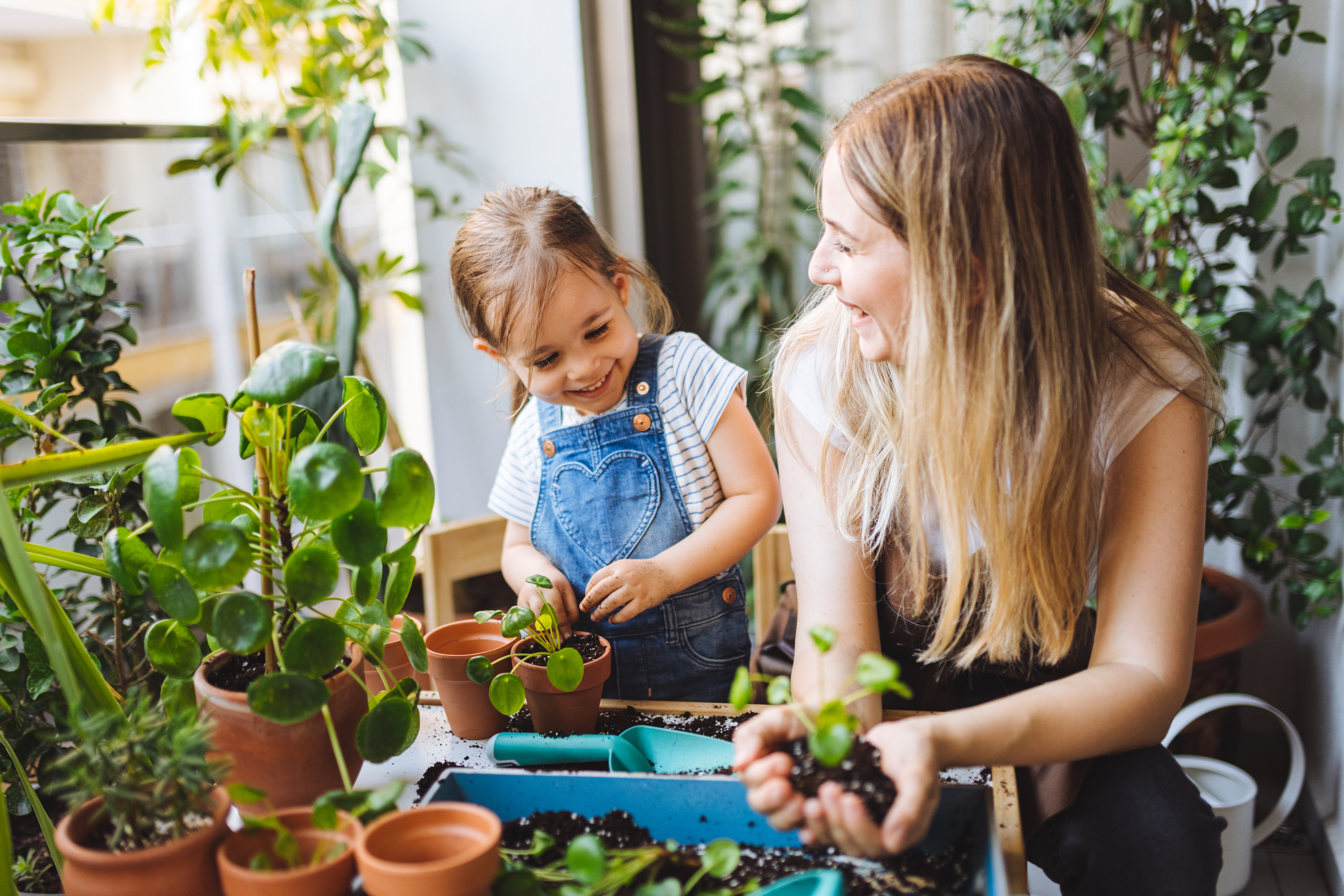Cute Girl Planting Flowers With Mother At House Balcony