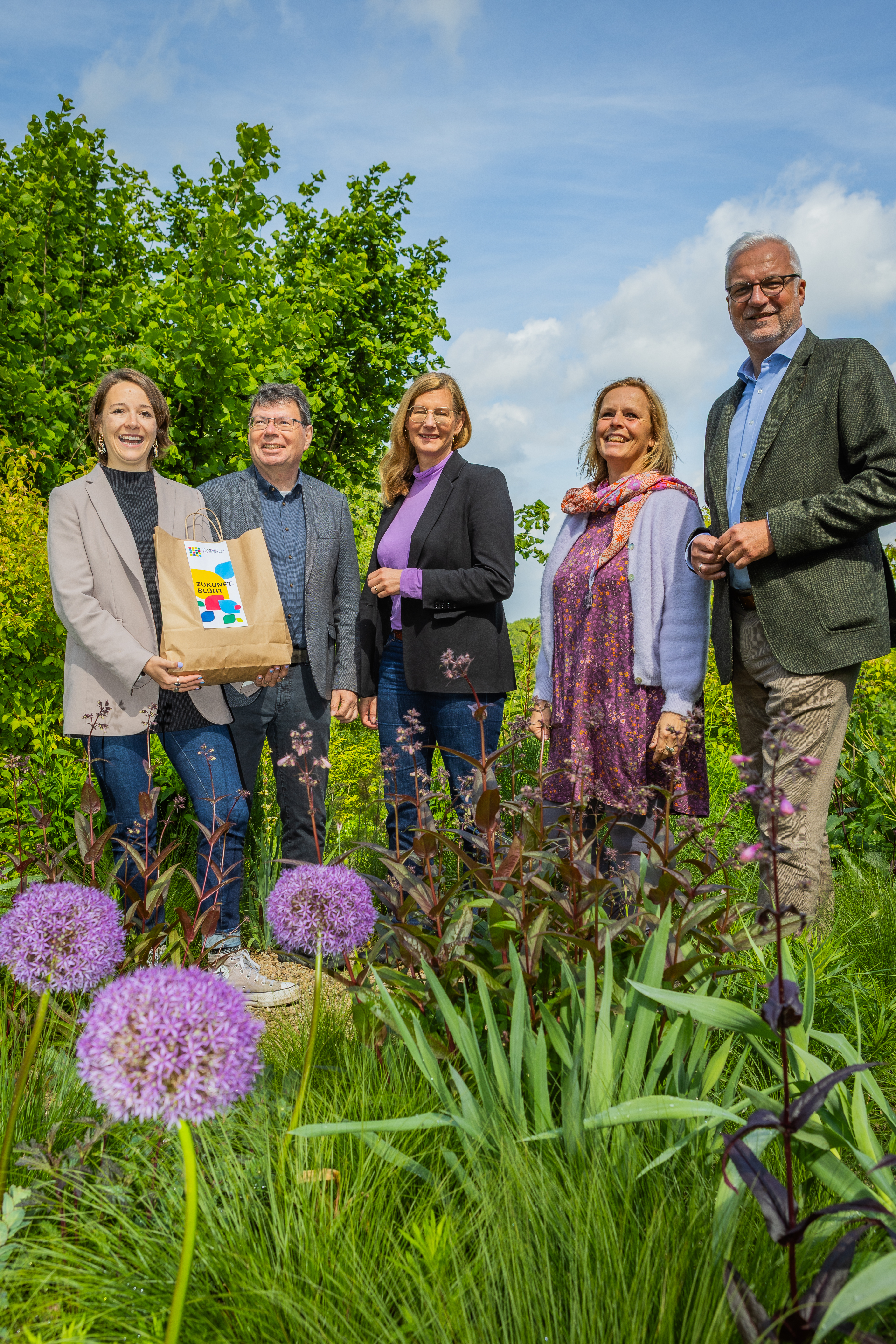 Fünf Personen stehen in einem Garten