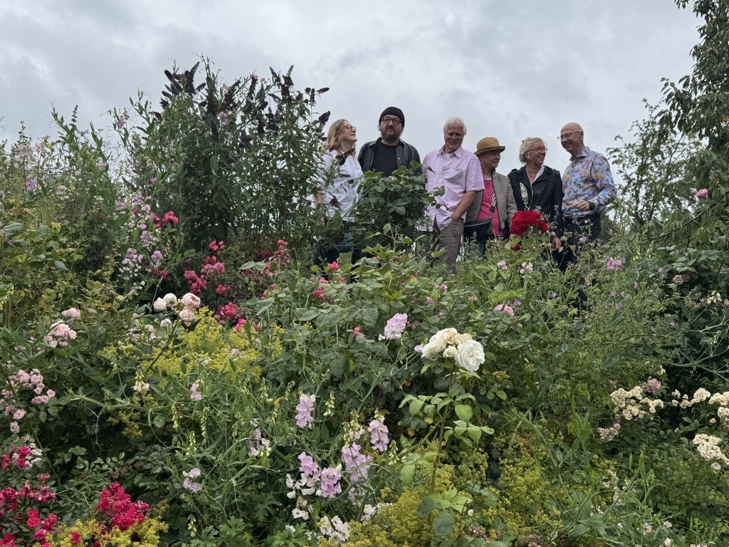 6 Personen stehen hinter Rosen