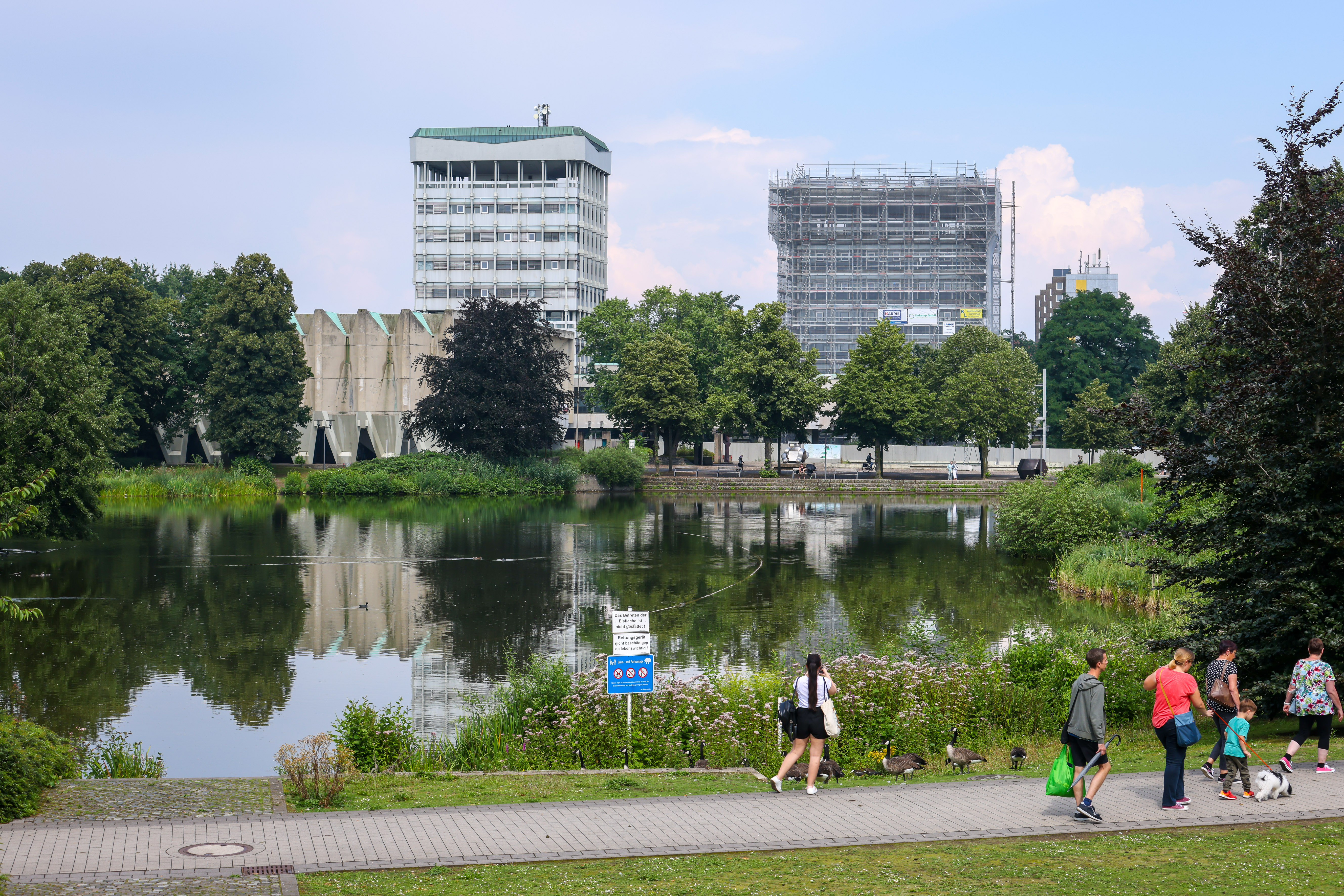 Blick auf die Fußgängerzone an einem See, dahinter städtische Gebäude