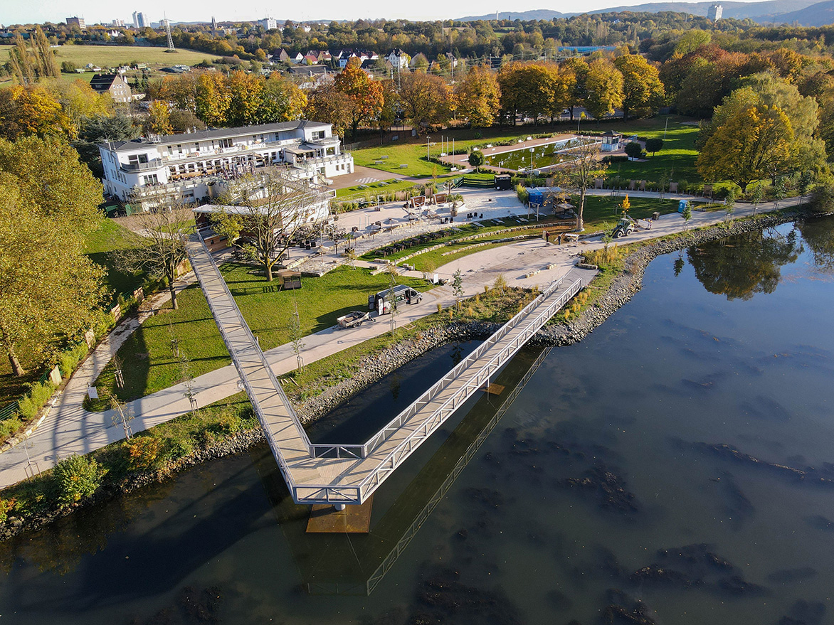 Vogelperspektive auf den Beachclub mit Steg, der halb über das Wasser führt
