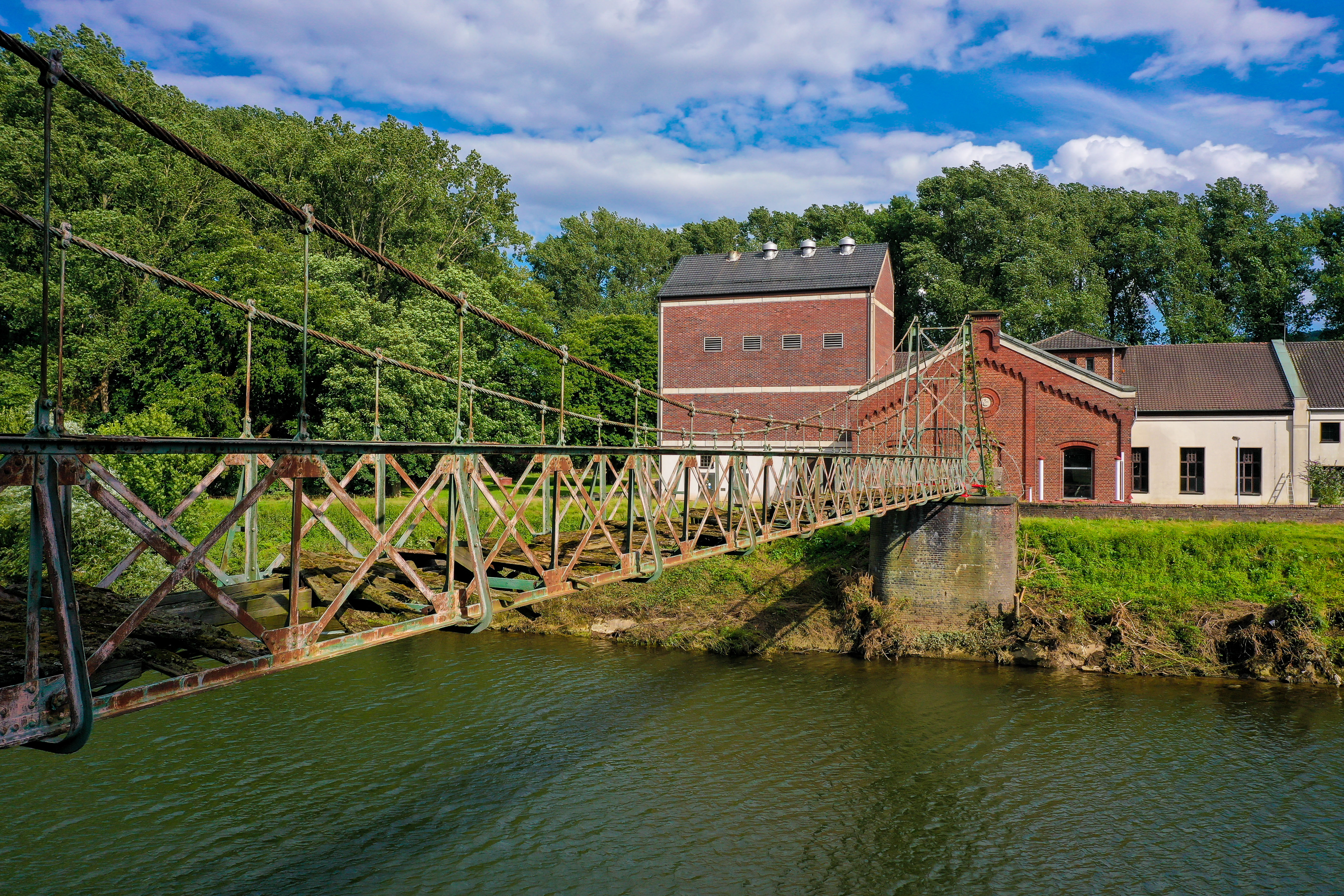 Blick auf die Seilhängebrücke und im Hintergrund das Wasserwerk in rotem Backstein